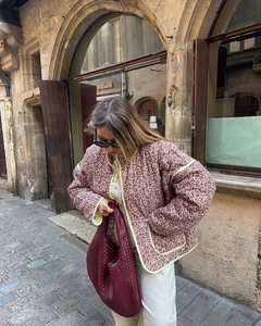 Detail of floral quilted cotton jacket with red-brown prints and woven tote bag