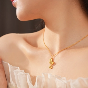 Detail of gold-plated necklace with pony and coin pendant shown on a female model