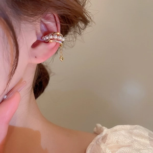 Detail of gold-plated multi-layer ear cuff with heart pendant, pearls and long chain on ear