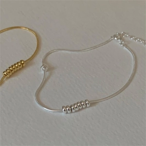 Detailed macro view of minimalist snake chain bracelets in silver and gold finishes