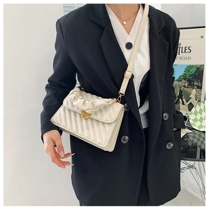 Chic beige crossbody bag with quilted texture and heart lock shown on model