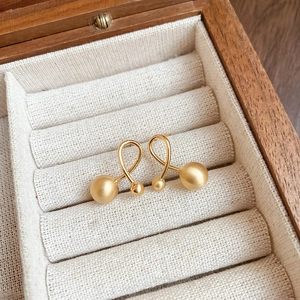 Minimalist gold-plated cross ball stud earrings with matte finish in a jewelry box