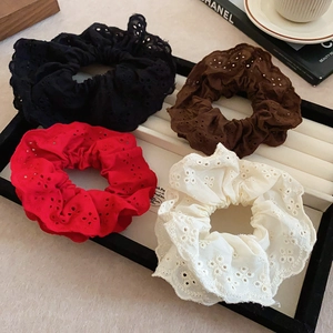 Detail of four double-layered hollow lace scrunchies in black, brown, red and beige colors