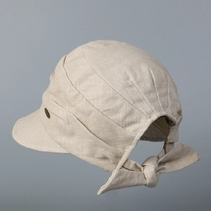 Detail view of cotton linen cap with metal button and back bow tie in oatmeal