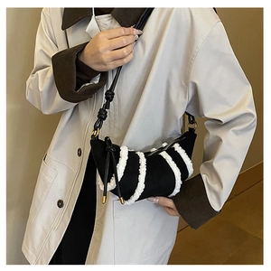 Detail der schwarzen Wildleder-Tasche mit weißen Vliesstreifen und Metall-Knotenspitzen