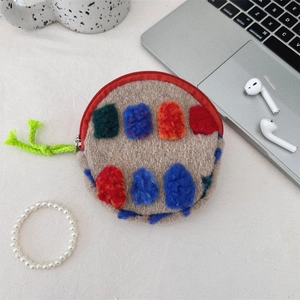 Macro view of plush round makeup bag with colorful felt balls on soft brown fabric