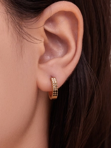 Macro view of gold hoop earrings with gradient pave crystals worn on the ear