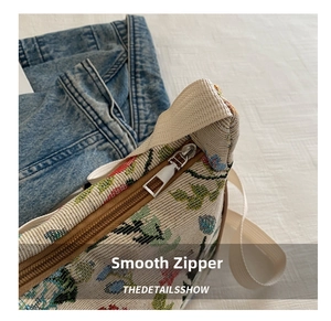 Close-up of silver metal zipper closure and floral jacquard canvas on a shoulder bag