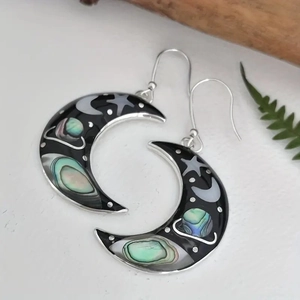 Detailed macro view of crescent moon earrings featuring celestial planet and star patterns