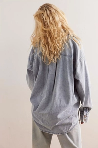 Rear view of long sleeve light blue denim shirt showing loose fit and yoke detail