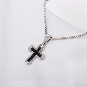 Silver cross necklace with black stone and diamonds on white silk background
