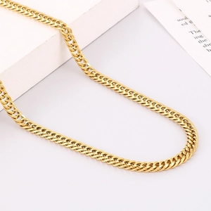 Detailed view of polished golden Cuban link chain necklace on a white geometric stand