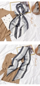 Detail of grey and white striped silk scarf tied on a khaki knit sweater with accessories