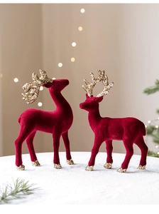 Close-up of red flocked reindeer figurines with golden glitter antlers on snow