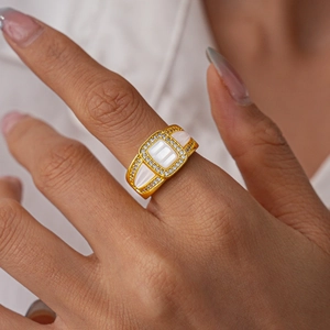 Détail macro d'une bague vintage dorée avec incrustations de résine blanche et zircons