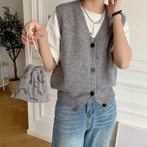 Gray corduroy bear storage drawstring bag held by model with knit vest outfit