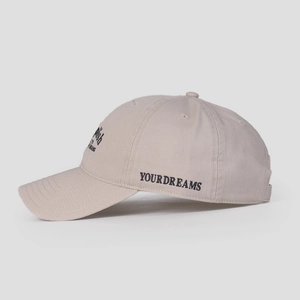 Detail of YOURDREAMS black embroidery on side of beige cotton baseball cap
