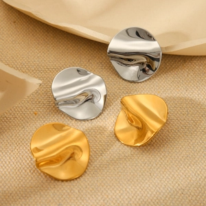 Detail of gold and silver irregular hammered wave stud earrings on beige linen texture