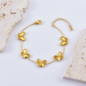 Golden double-sided embossed butterfly charm bracelet on stone display stand