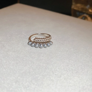Detail view of silver wheat ear ring with elegant grey pearl accents on white stand