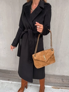 Detail of black wool coat paired with brown suede handbag and tall boots in street style