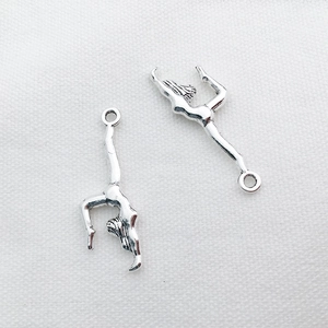 Dettaglio di ciondoli ginnasta in argento su tessuto bianco per braccialetti fai-da-te