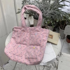 Detail of pink plush tote bag with colorful textured stripes and four buttoned pockets