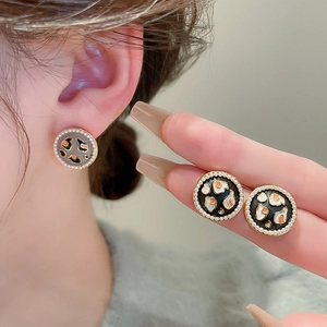 Detailed macro view of vintage round earrings with leopard pattern and faux pearls