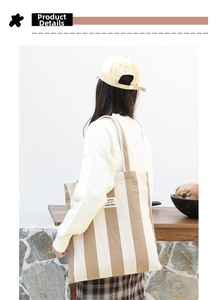 Detailed view of canvas tote with SEASON 12 woven label and striped shoulder straps