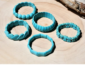 Detailed flat lay of five different geometric turquoise stretch bracelets on wood