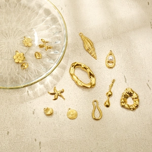 Detailed close-up of various gold charms including starfish and shells for DIY jewelry