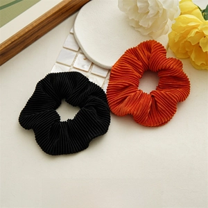 Detail of orange and black pleated scrunchies on a decorative display with floral props