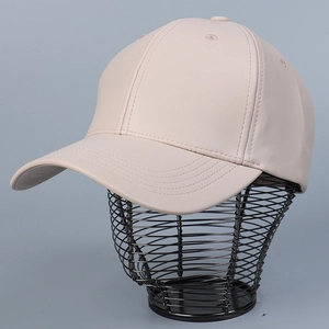 Detailed view of cream PU leather baseball cap with a textured finish on a display stand