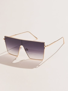 Close-up of oversized square sunglasses with gold metal frame and purple gradient lenses