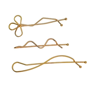 Three-piece gold alloy hair clip set with clover, wave, and cross designs on white background