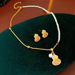Parure de bijoux gourde plaquée or 18K avec perles blanches sur support en velours vert