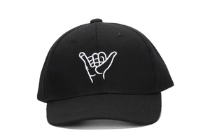 Close-up of white Shaka finger embroidery on a black cotton twill baseball cap