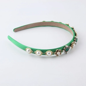 Close-up of green satin headband with baroque emerald gems and faux pearls decoration