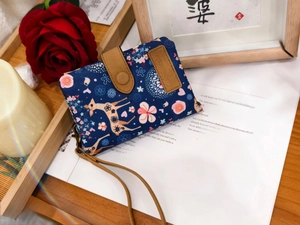 Detail of blue canvas wallet with floral deer print and matching wristlet on a magazine