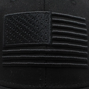 Detail of all-black American flag embroidery on a cotton twill baseball cap with matte finish