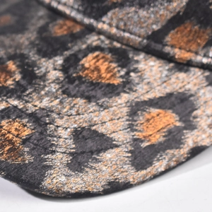 Macro shot of metallic gold leopard print fabric texture on a structured baseball cap