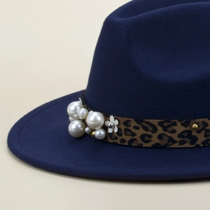 Détail du chapeau fedora bleu foncé avec ruban léopard, perles et ornements floraux