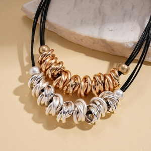 Chic multi-layer black cord necklace with mixed gold and silver geometric rings on stone