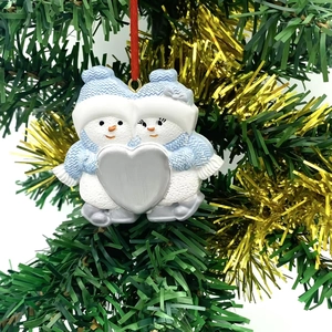 Detail of custom resin snowman ornament with red ribbon hanging on a decorated Xmas tree