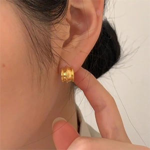 Close-up of model wearing gold multilayer curved 925 silver earrings with texture