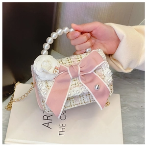 Close-up of pink tweed mini bag with pearl handle, ribbon bow, and camellia charm