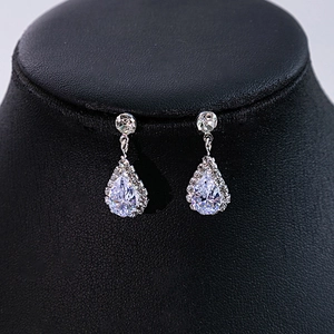 Detailed macro view of pear-shaped zircon bridal earrings on a black leather display