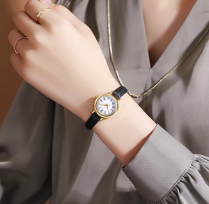 Elegant gold vintage women's watch with black leather strap on model's wrist