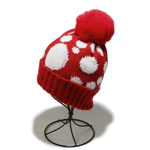 Detail der roten Strickmütze mit weißen Punkten, Bommel und geripptem Umschlag