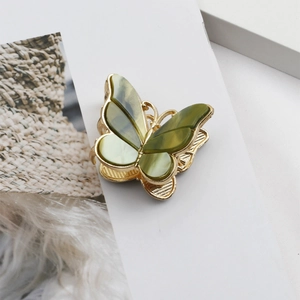 Detail of a vintage golden butterfly hair claw clip with green marbled wing accents